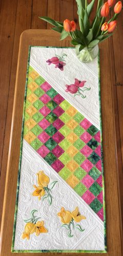 Finished tablerunner with pieced multi-colored center and embroidery on ivory ends.