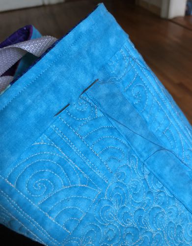The raw edge of the strip folded and sewn to the tote's lining.