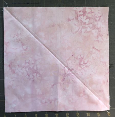 Pink square on a white square stitched on both side of a diagonal.