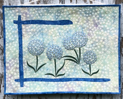 Small quilt in blue and grey colors with embroidery of allium flowers