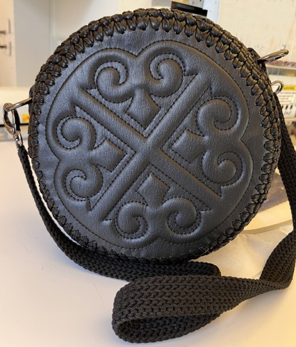 A shoulder bag with embroidered front and bag panels and crocheted side panel and handle.