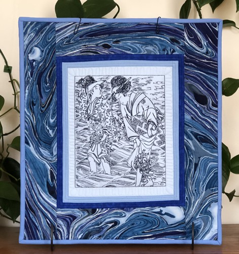 Small quilt in blue hues with one-color embroidery of a Japanese picture of women by the sea.