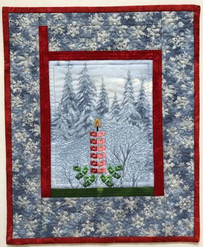 Small quilt with embroidery of a Christmas candle on blue background