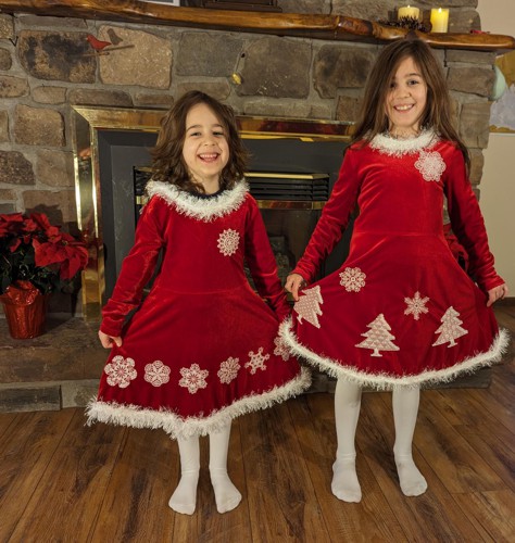 2 girls in red velvet dresses decorated with embroidery