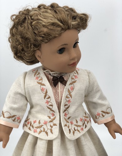 A doll in linen jacket with embroidered bodice and sleeves. Front view.