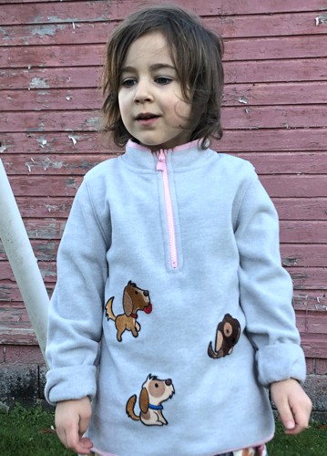 A girl in a gray sweatshirt decorated with puppies embroidery