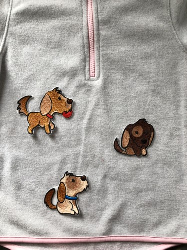 Stitch-outs of the puppies on a gray sweater.