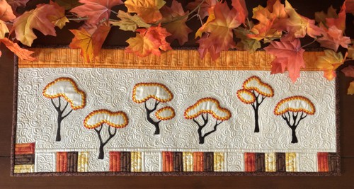 A small wall quilt or table runner with autumn trees embroidery