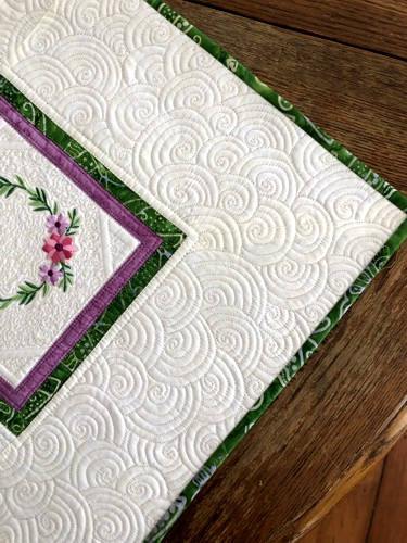Close-up of the embroidery, quilting stitches and binding.