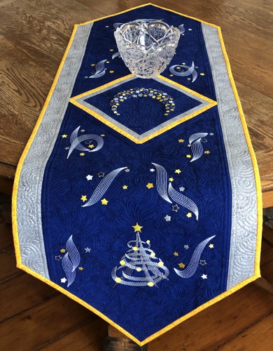 Royal blue quilted tablerunner with embroidery of a moon, stars and Christmas trees in silver and golden colors