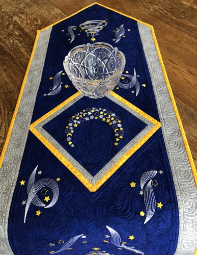 Royal blue quilted tablerunner with embroidery of a moon, stars and Christmas trees in silver and golden colors