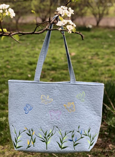 Finished tote bag with embroidery of grass and butterflies on the front and back panels.