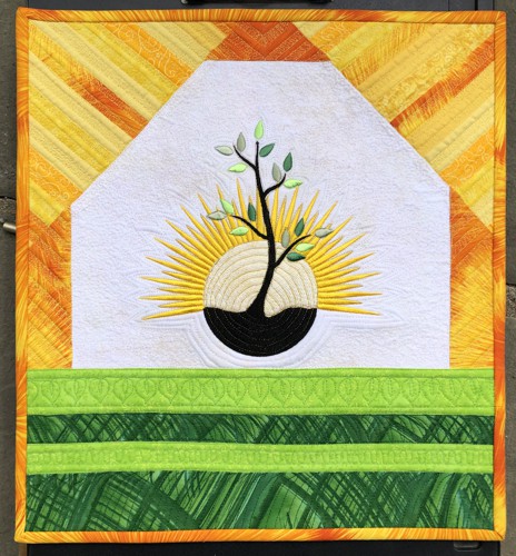 Small wall quilt with embroidery of a tree and rising sun in bright golden and green colors