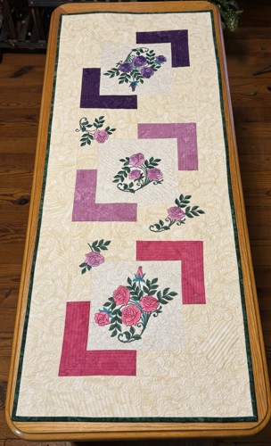 Finished quilted tablerunner with embroidery of camellias in pink, lilac and purple shades