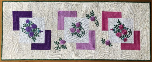 Finished quilted tablerunner with embroidery of camellias in pink, lilac and purple shades