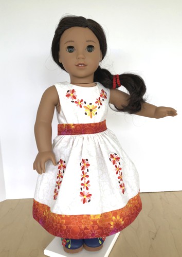 A doll in finished skirt and top with embroidery on bodice and skirt.
