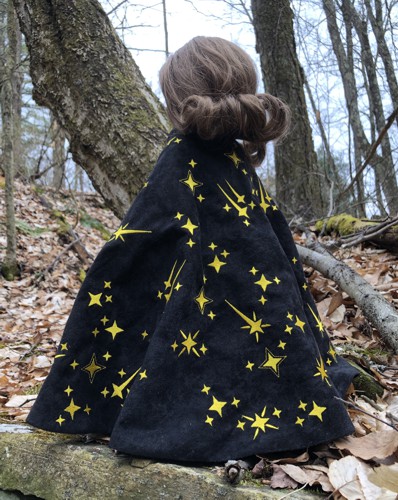 A 18-inch doll in a black cape embroidered with golden stars
