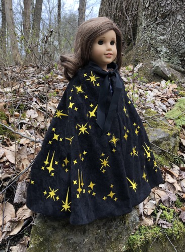 A 18-inch doll in a black cape embroidered with golden stars