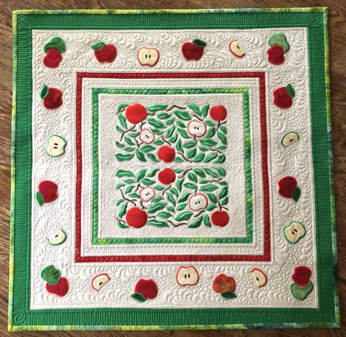Finished tabletopper with embroidery of the apples in the center and apple applique on the borders.
