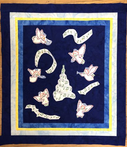 Paper printouts of the designs show the position of the embroidery on the central part of the quilt.