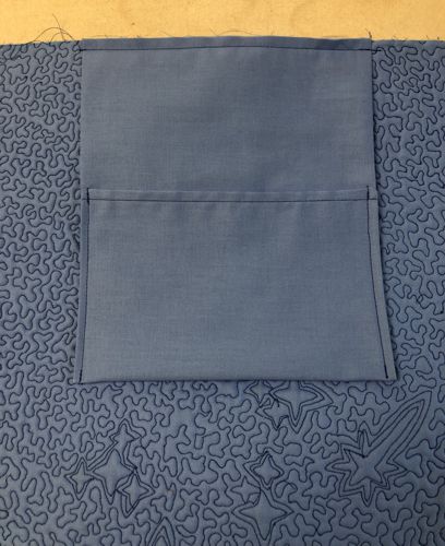 Pocket is attached to the upper edge of the back panel.