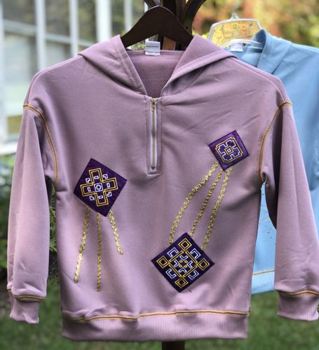 The finished lilac sweater with the kites applique embroidery.