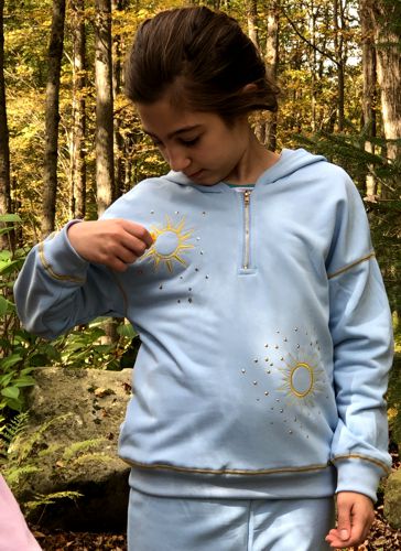 A girl in a sky-blue sweater with sun embroidery