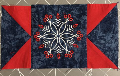 2 flying geese units stitched to the sides of the embroidered square.