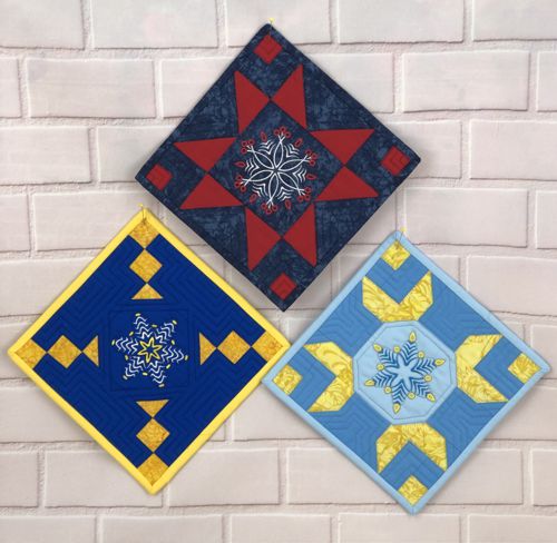 3 quilted pieces as decorative pot holders on a wall.