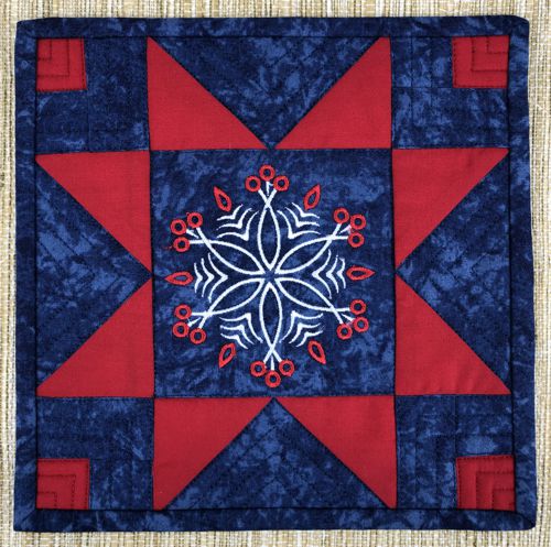 Finished mug rug with a snowflake in the center in blue and red colors.