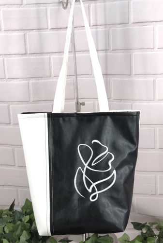 Finished white-and-black bag with embroidery of an abstract flower on the back panel.