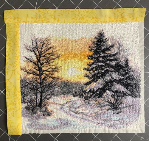 Yellow borders are stitched to the upper and left edges of the stitch-out.