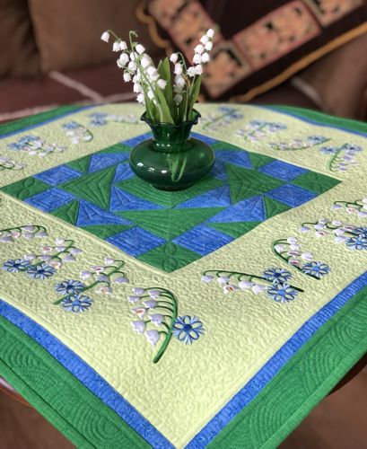 Quilted tabletopper with lily of the valley embroidery.