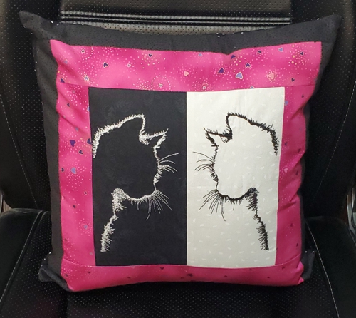 Black and pink pillow with black and white embroidered center. Embroidery design is cat silhouettes.